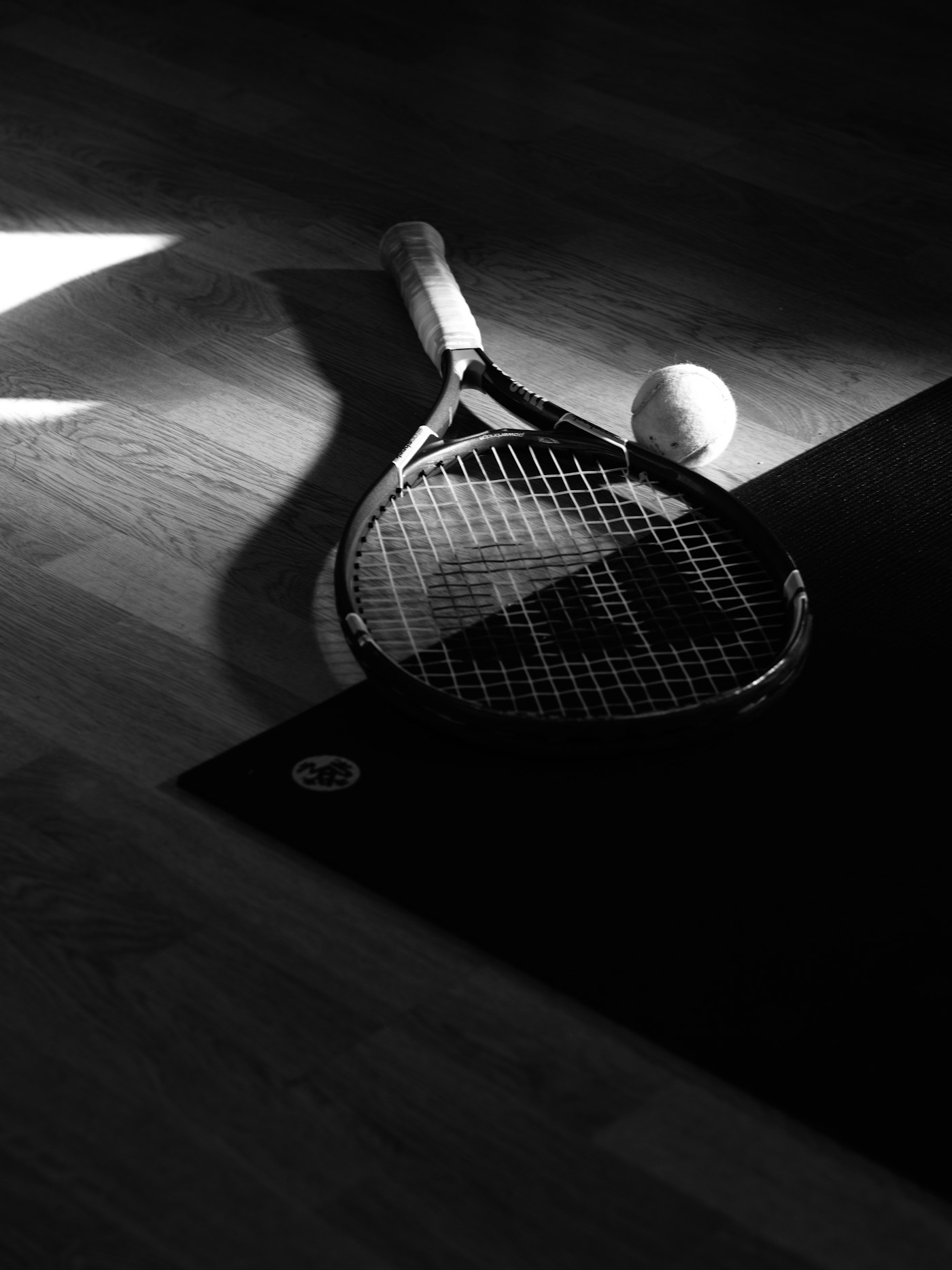Racket and ball arranged in a quiet black-and-white still life