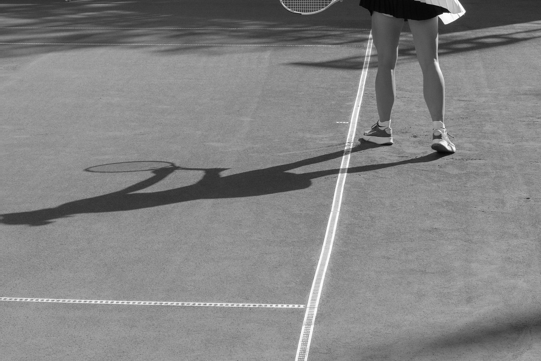 Player shadow stretching across a clay court