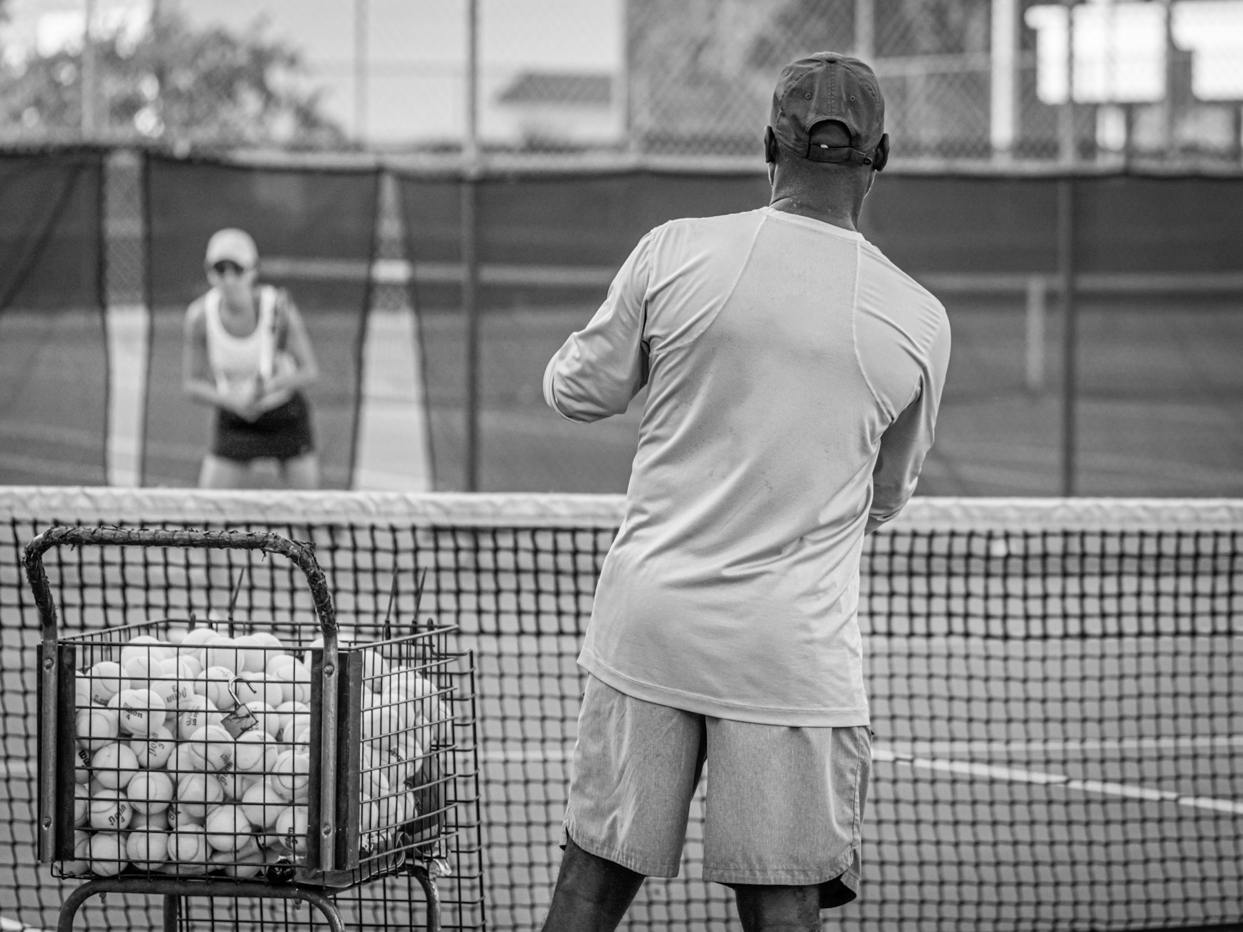 Coach feeding balls across the net during a live drill
