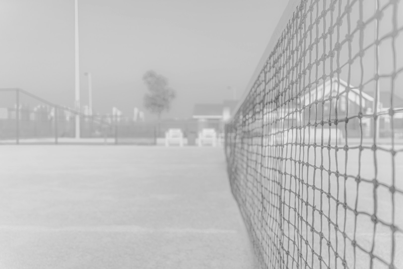 Black-and-white tennis session frame with court action and strong contrast
