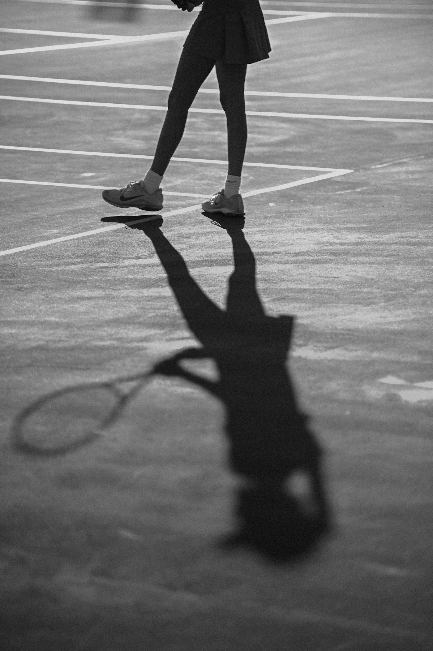 Long player shadow stretched over a marked court