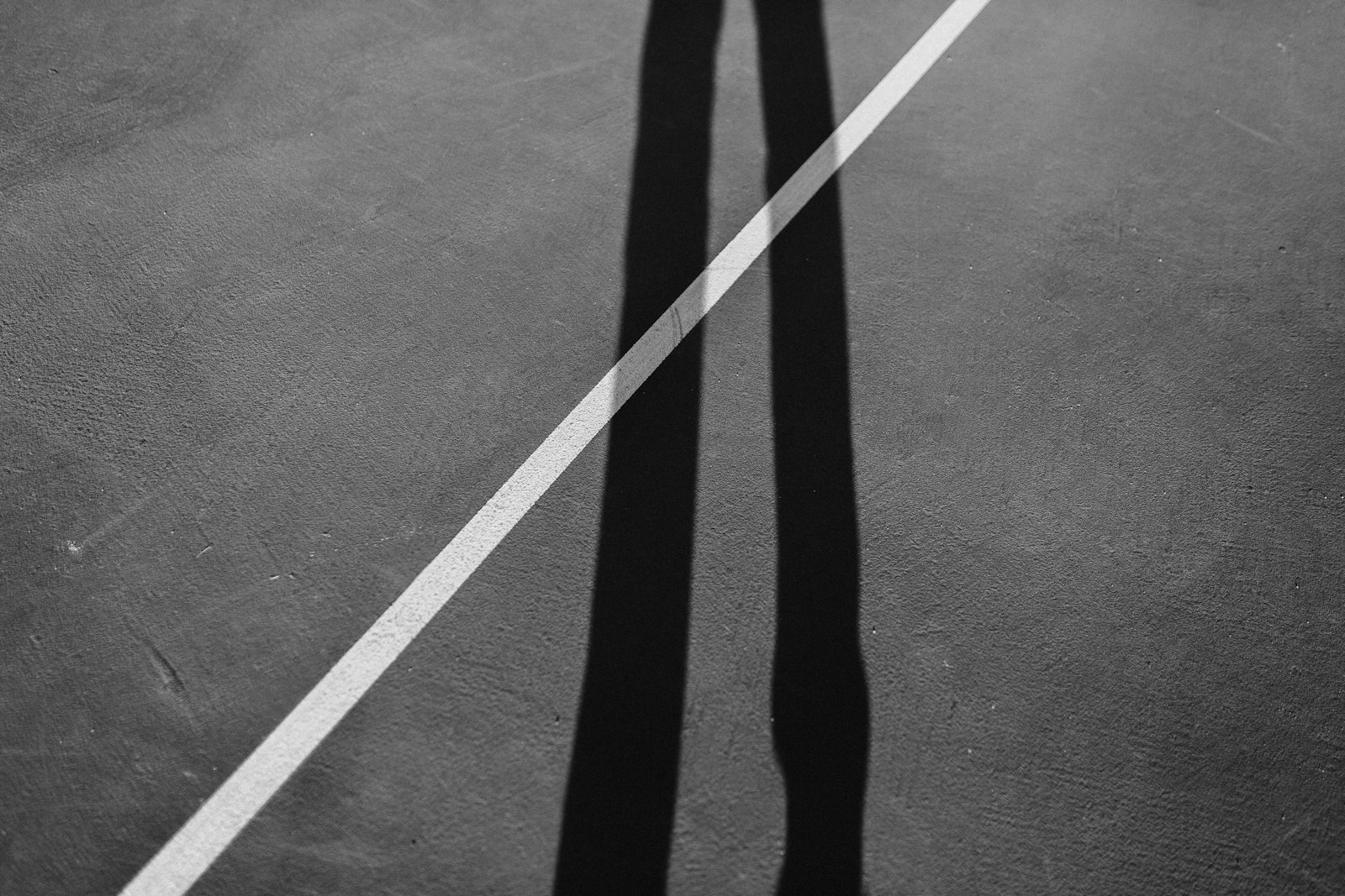 Court lines cutting through a tall player shadow